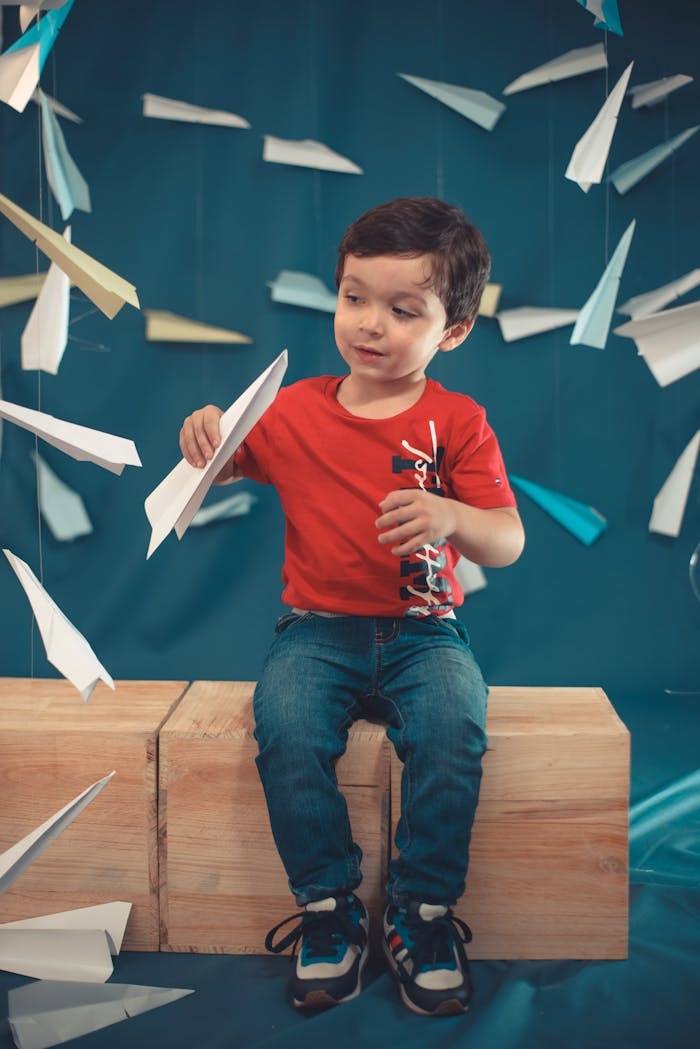 our-story A child creatively interacts with paper airplanes, enhancing education and fun in a playful indoor setting.