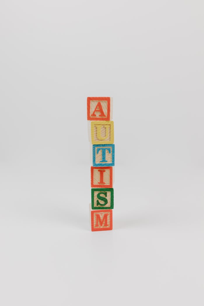 about-us Vertical stack of colorful wooden blocks spelling 'AUTISM' on a white background.