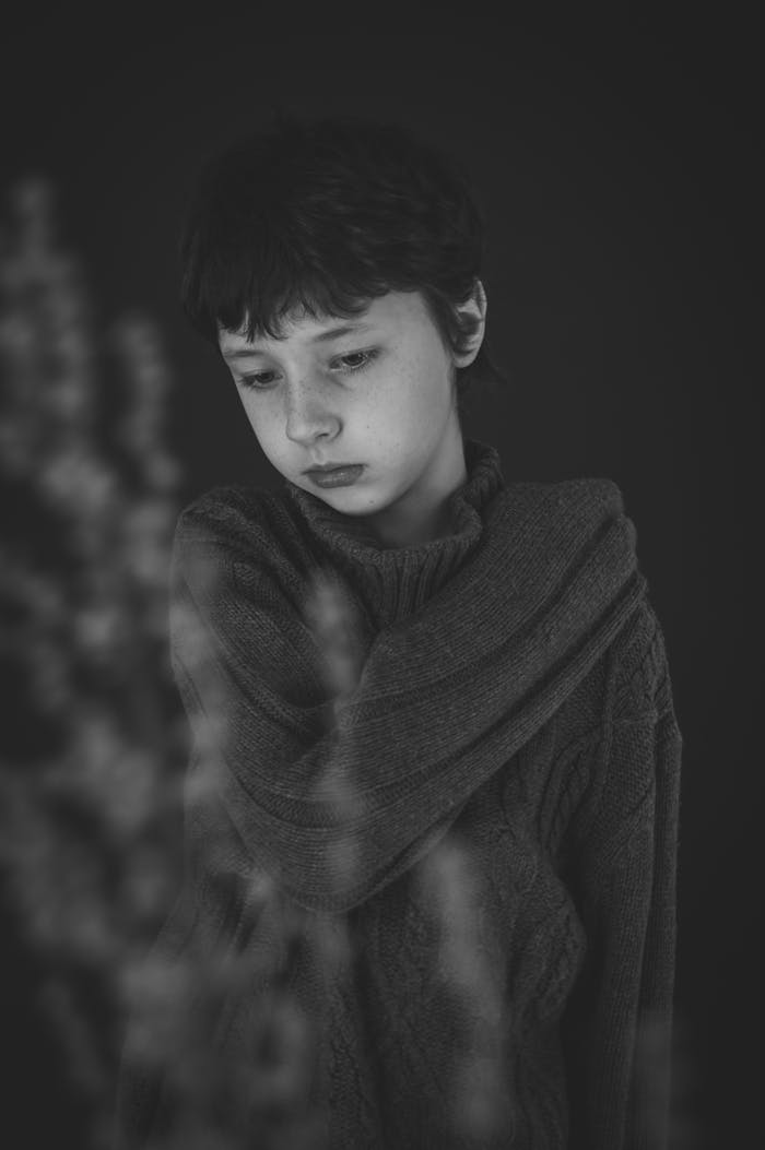 A black and white portrait of a child wearing a sweater, conveying a contemplative mood.